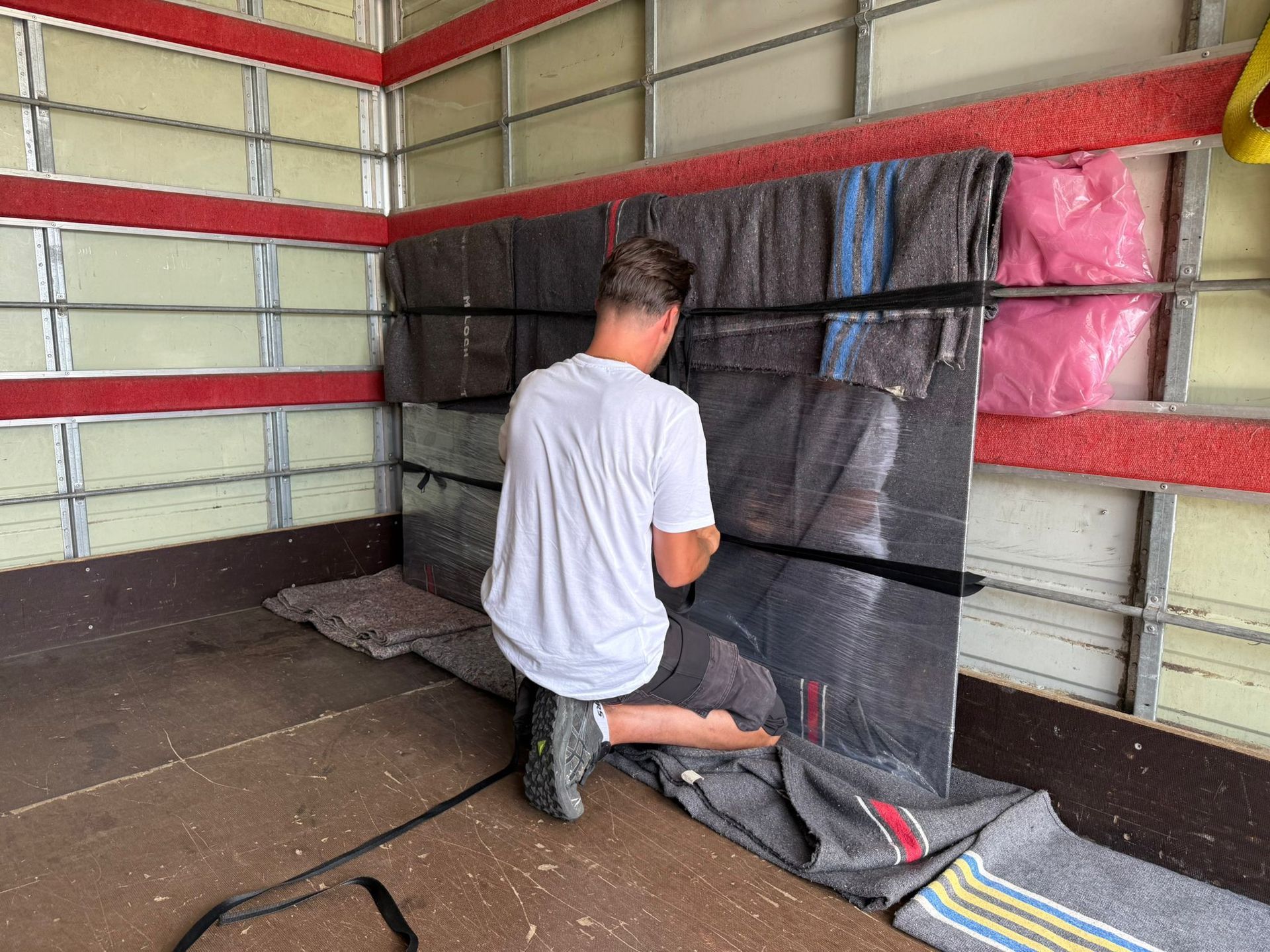 Deux camions de déménagement garés devant une maison, des déménageurs chargeant des meubles. Journée ensoleillée, ciel bleu.