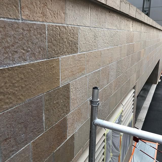 Mur en briques de pierre, partiellement nettoyé, échafaudage sous les fenêtres.