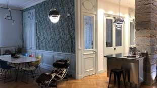 Intérieur d'appartement élégant : coin repas avec table en marbre, mur tapissé, cuisine avec îlot en acier inoxydable.