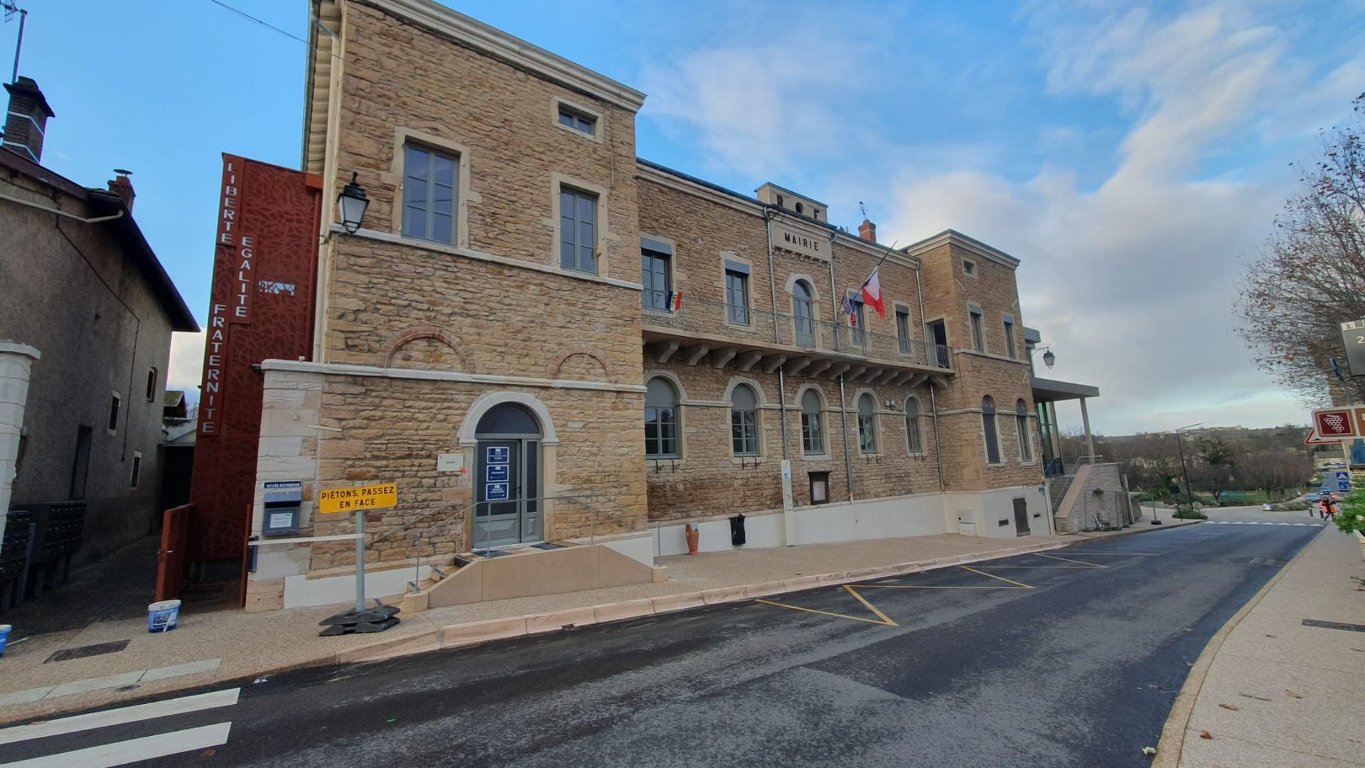 Immeuble en pierre avec drapeau français sur le balcon.