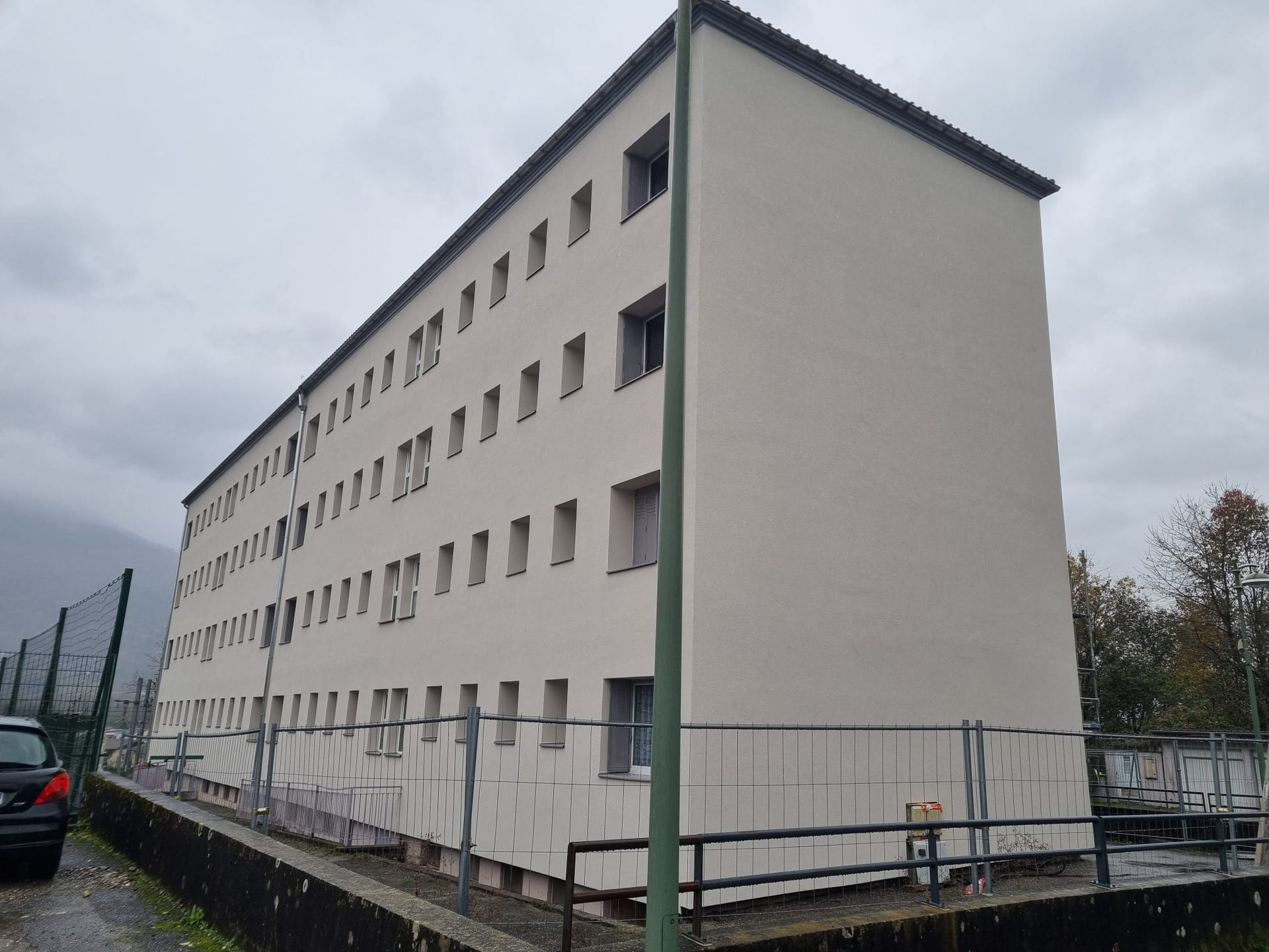 Façade blanche d'une maison avec des volets et un parassol devant.