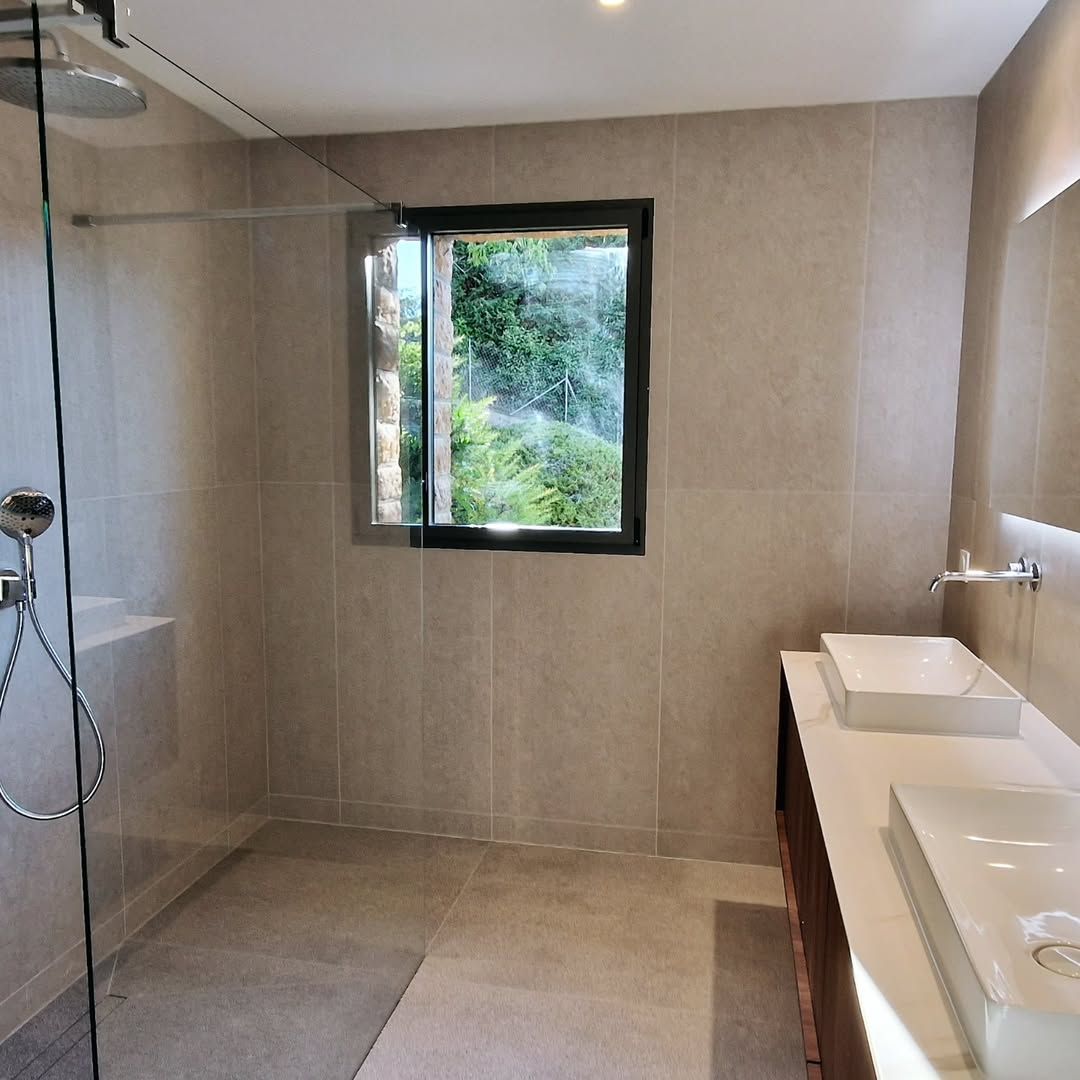 Salle de bains avec douche à l'italienne, fenêtre et double vasque.