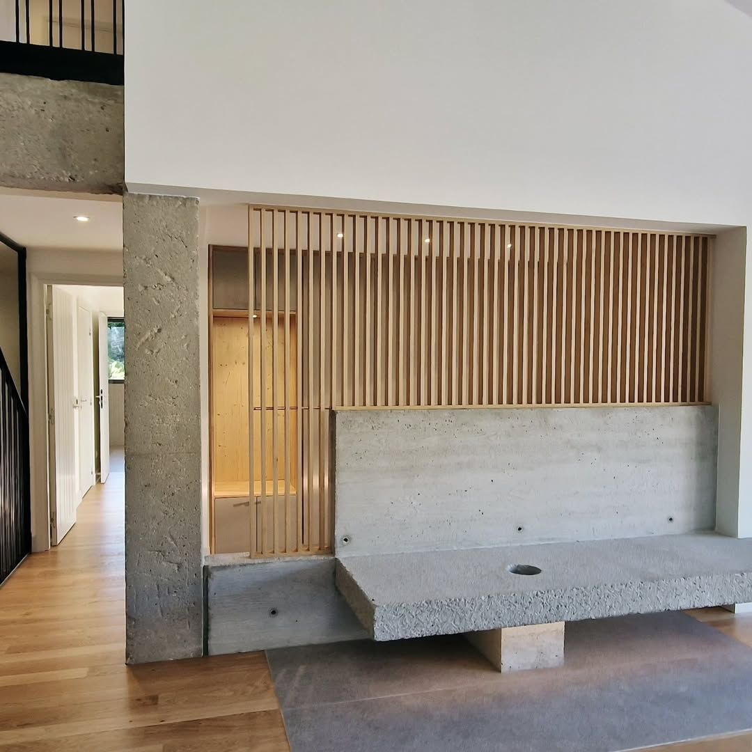 Banc en béton avec écran en bois contre un mur blanc ; vue intérieure.