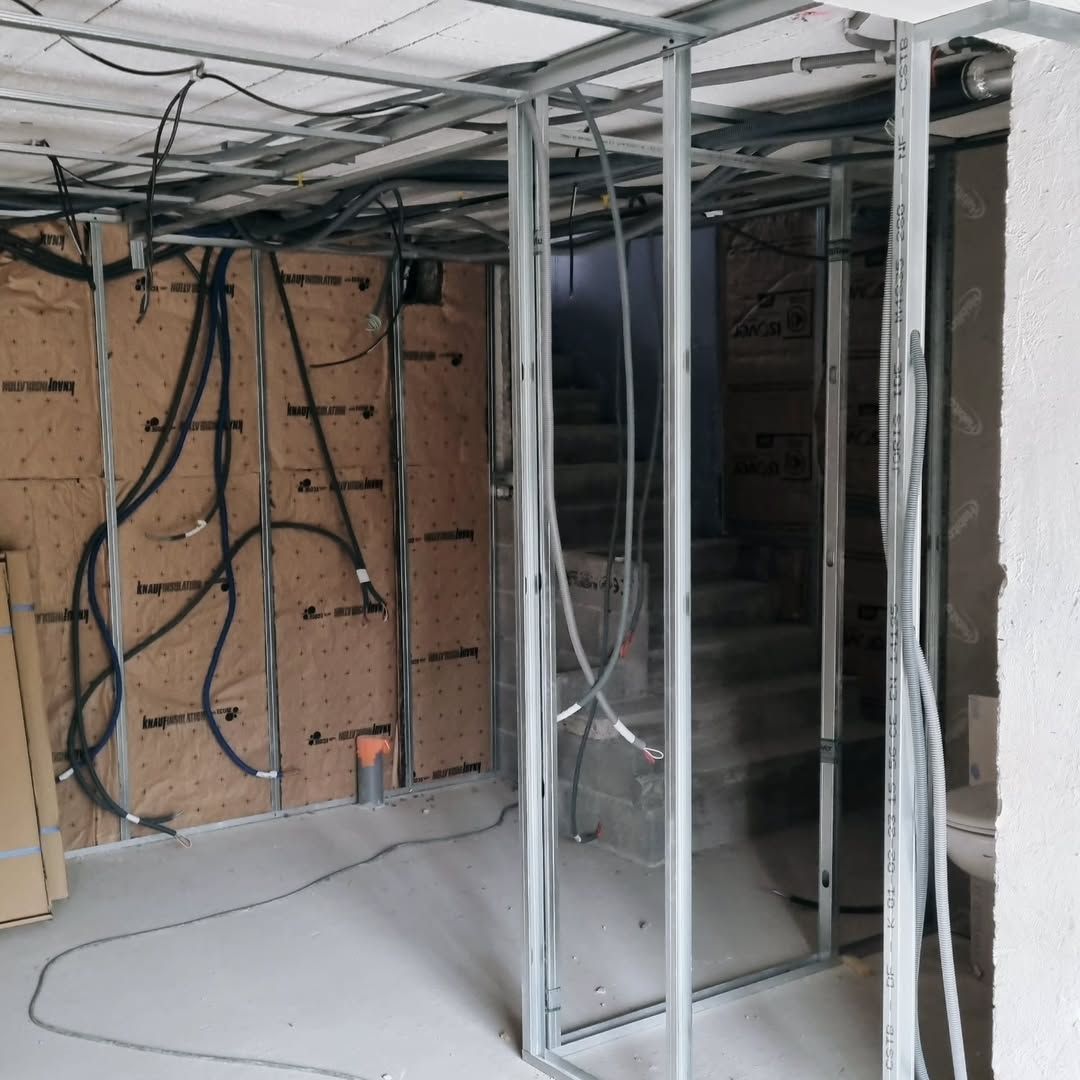 Charpente de construction intérieure avec fils apparents, isolation et escaliers.