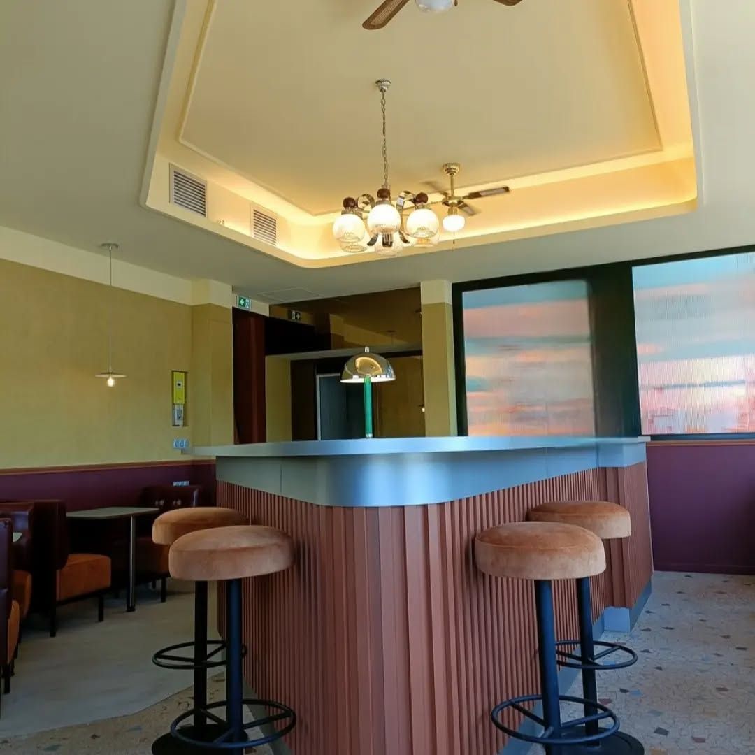 Bar-restaurant rétro avec tabourets et plafond à motifs, avec une fenêtre en arrière-plan.