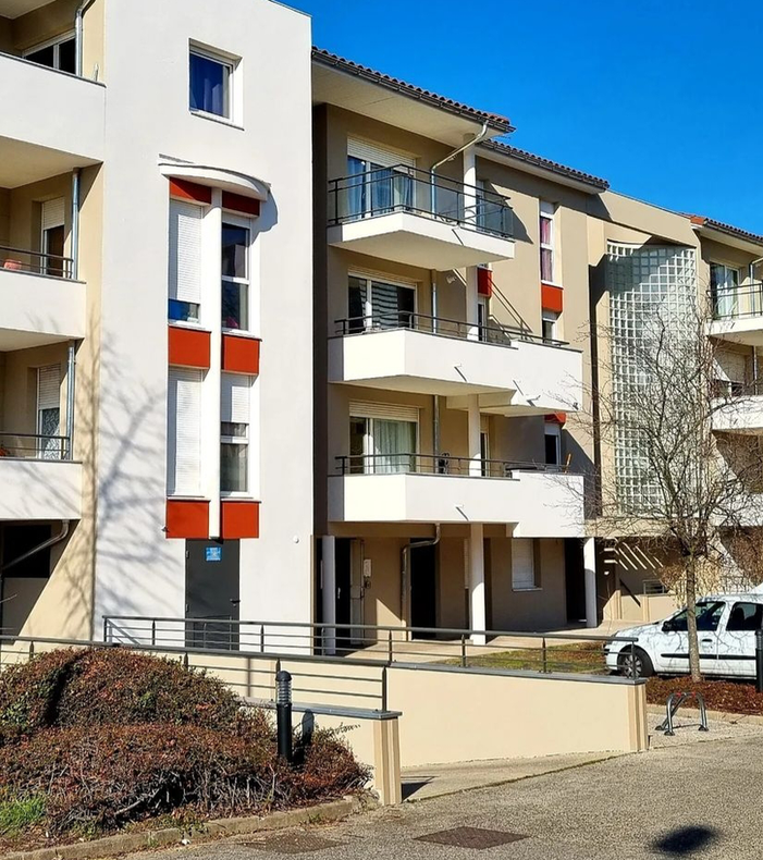 Bâtiment blanc avec balcons sur fond de ciel bleu.