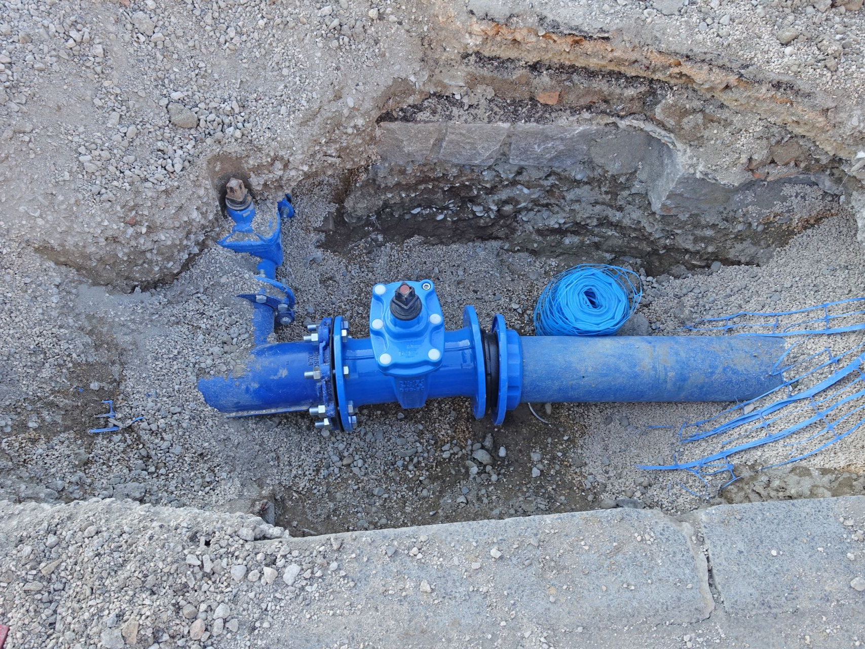Installation d'un tuyau bleu dans une tranchée