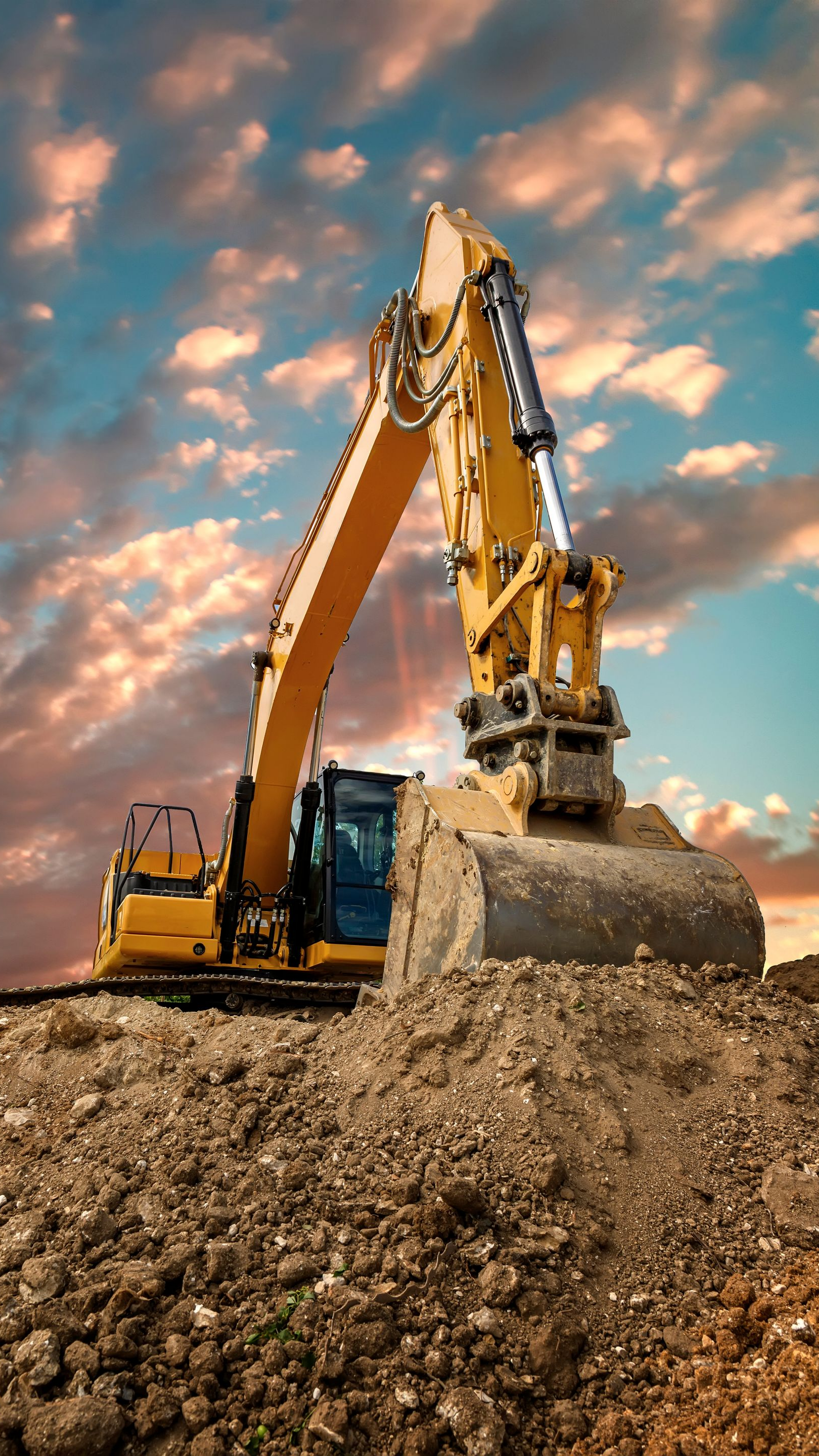Une tractopelle jaune devant un ciel avec des nuages orangés