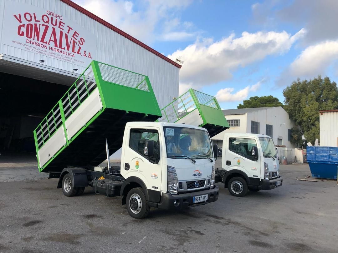 Dos camiones de volteo están estacionados frente a un edificio.