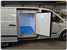 Una furgoneta blanca con las puertas abiertas y el suelo azul.