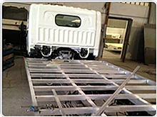 Un camión blanco está estacionado encima de una plataforma de metal en un garaje.