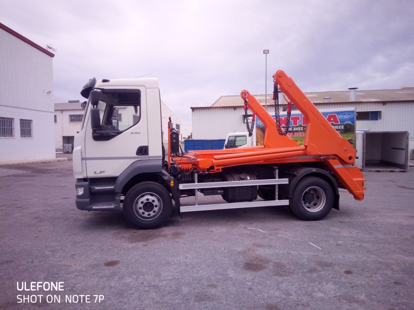 Un camión de volteo está estacionado en un estacionamiento al lado de un edificio.
