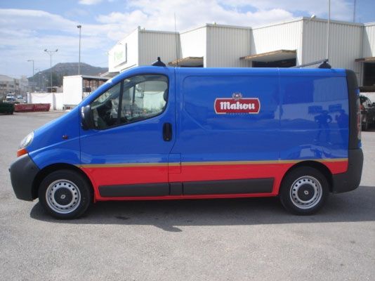 Una furgoneta Mahou azul y roja está aparcada en un aparcamiento.