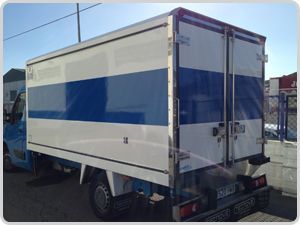 Un camión azul y blanco está estacionado al costado de la carretera.