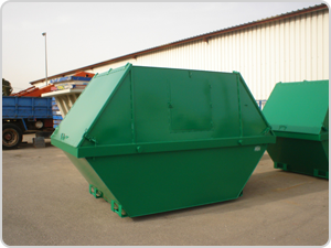 Un contenedor de basura verde está frente a un edificio.