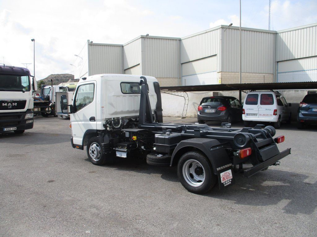 Un camión blanco con un remolque negro está estacionado en un estacionamiento.