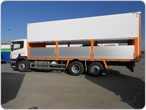 Un camión blanco con detalles en naranja está estacionado en un estacionamiento.