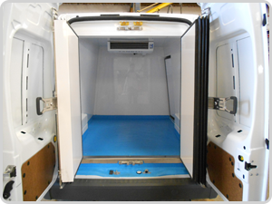 El interior de una furgoneta blanca con una alfombra azul en el suelo.