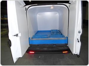 La parte trasera de una camioneta blanca con las puertas abiertas y una bandeja azul en la parte trasera.