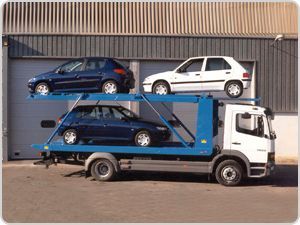 Una grúa azul y blanca con tres coches encima.