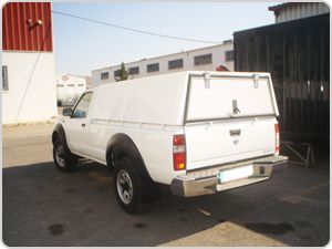 Un camión blanco con toldo está estacionado frente a un edificio.
