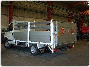 Un camión blanco con una jaula en la parte trasera está estacionado en un garaje.