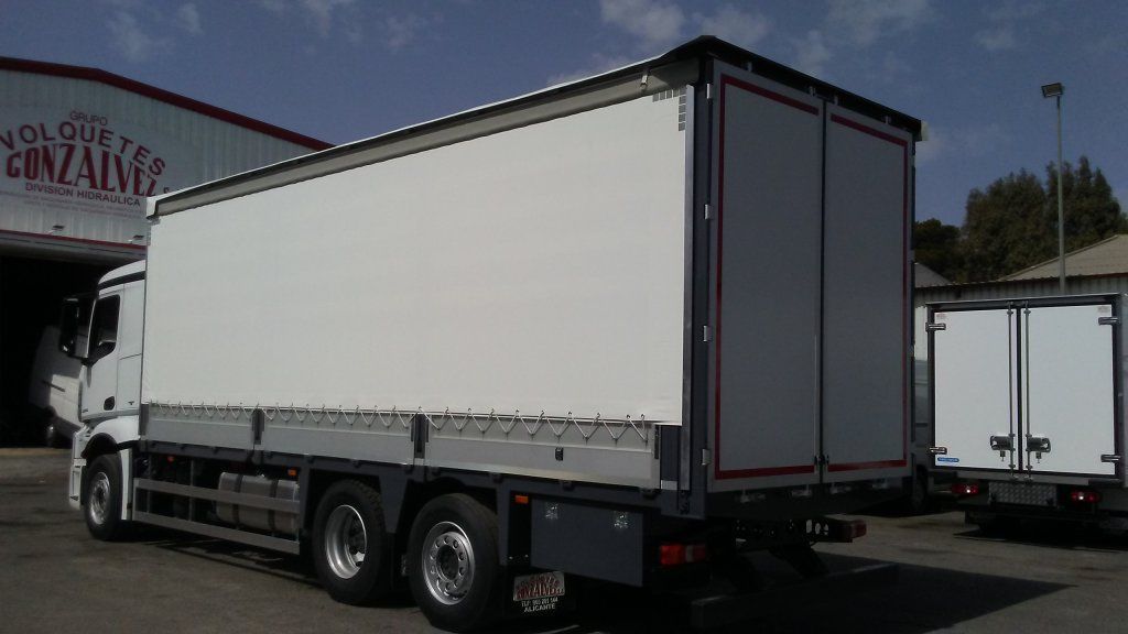 Un camión blanco está estacionado frente a un edificio que dice Gonzalo.