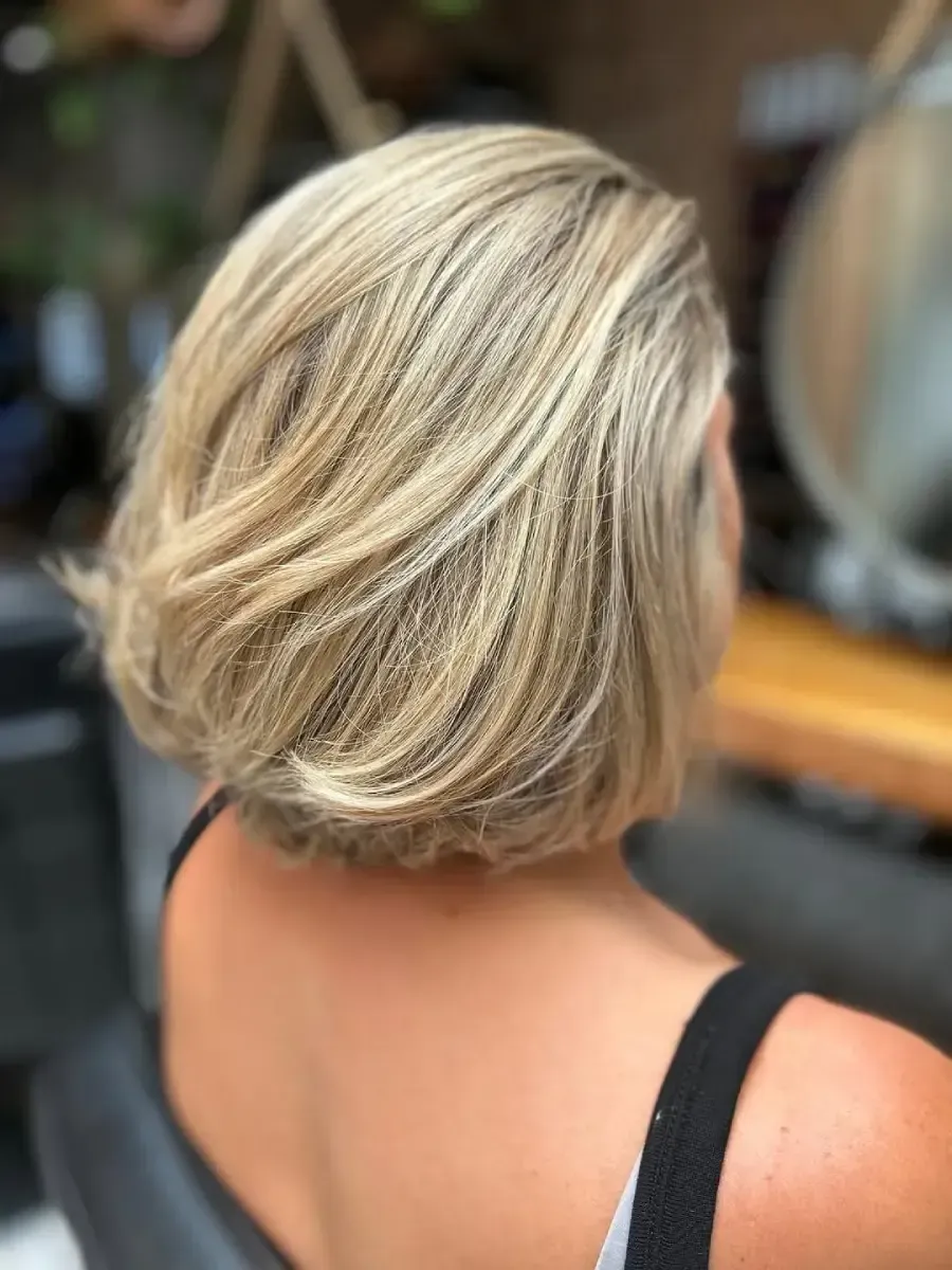 Peinado bob rubio corto visto desde atrás en un salón de belleza.