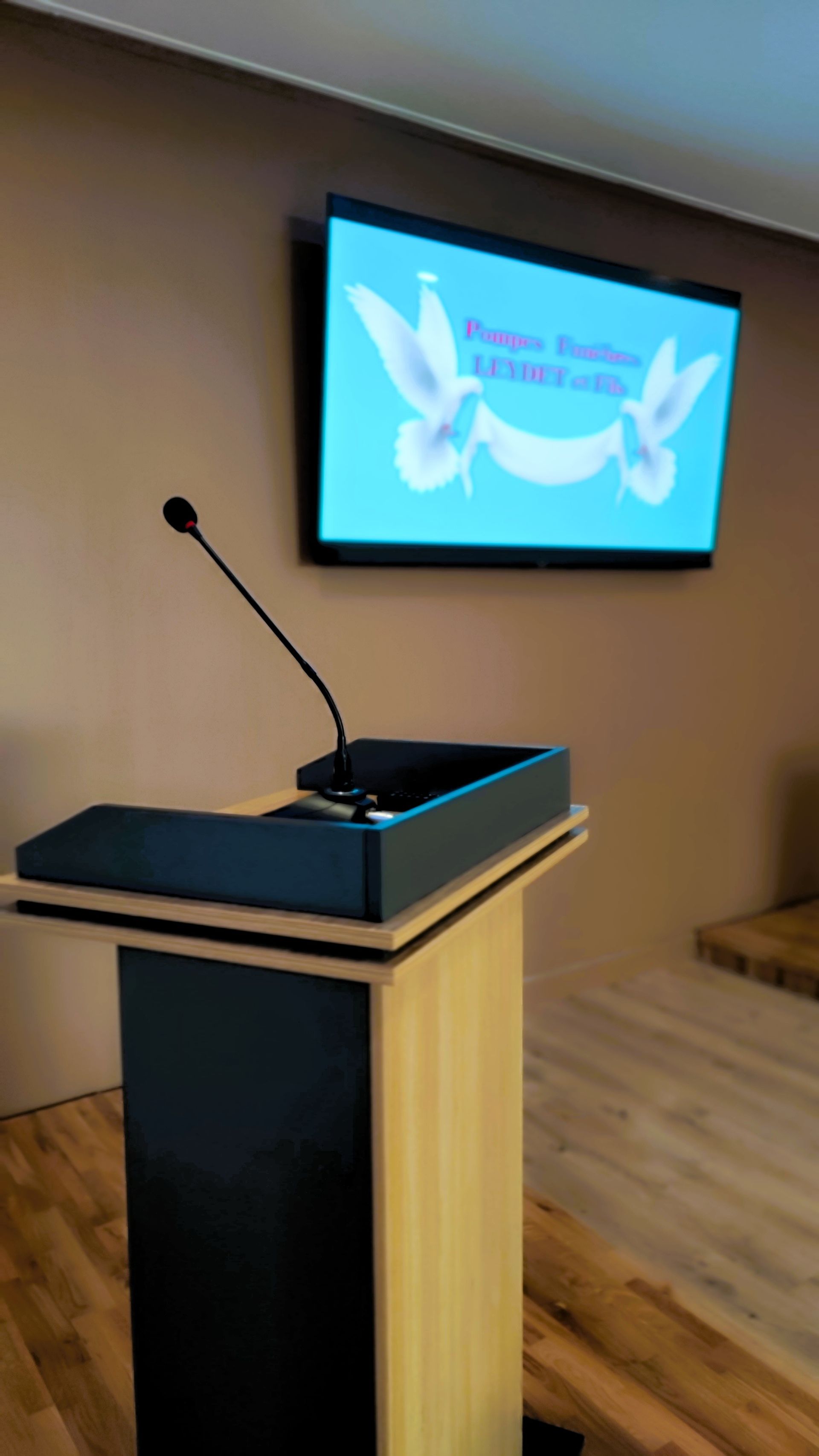 Pupitre dans une salle de cérémonie, avec une télévision accrochée au mur