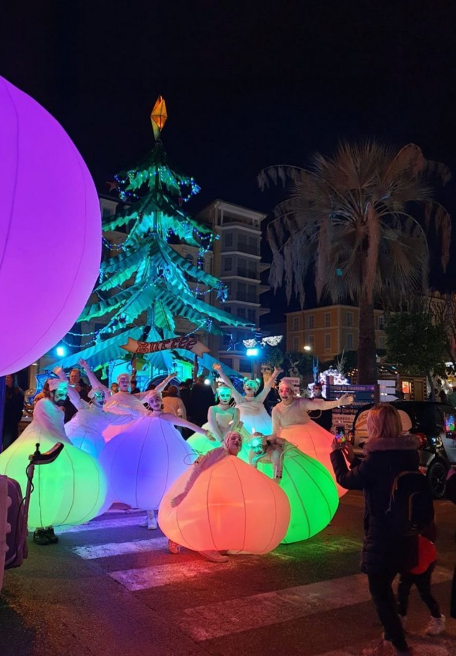 Un grupo de personas está bailando delante de un árbol de Navidad.
