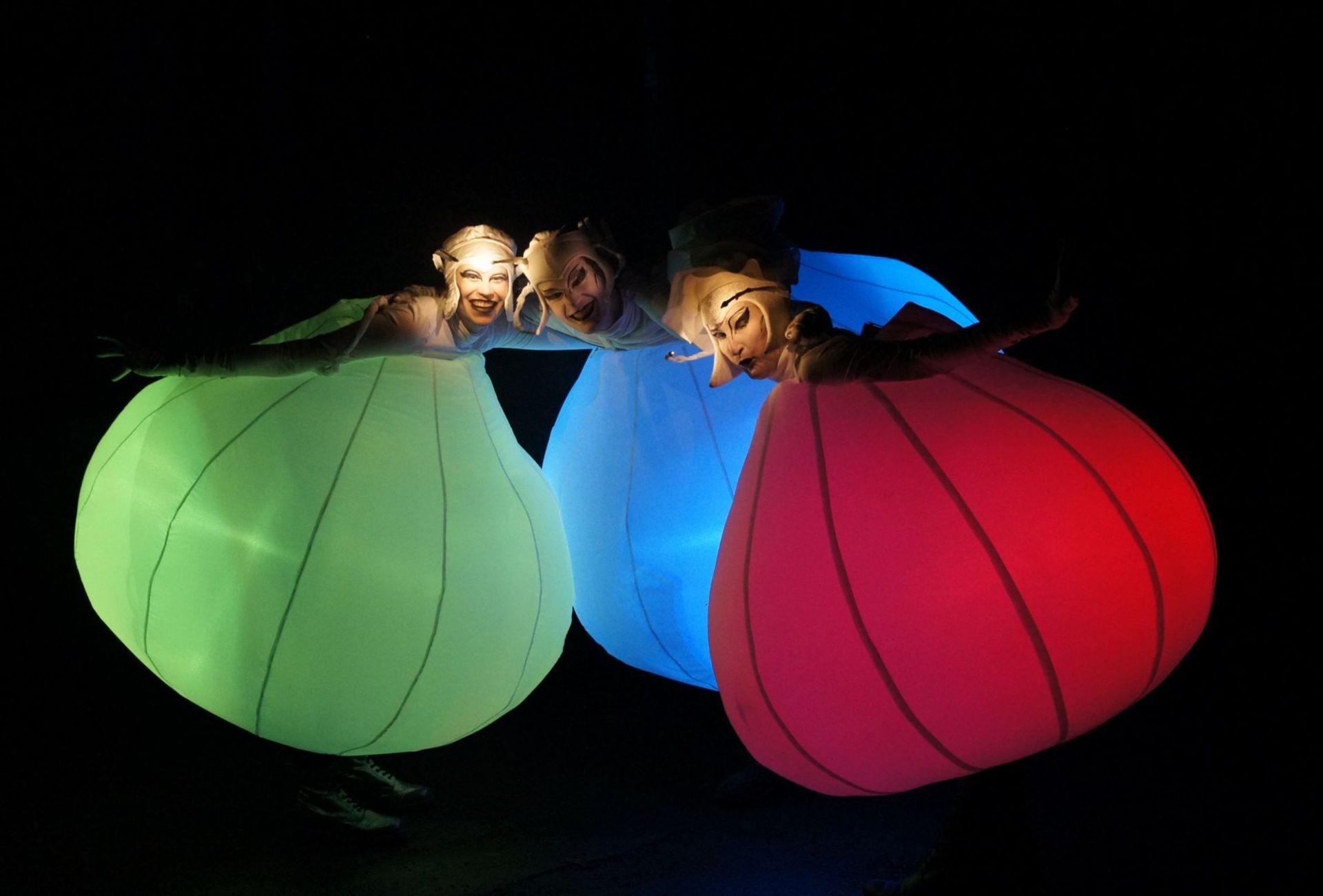 Un grupo de personas están paradas una al lado de la otra usando globos que brillan en la oscuridad.