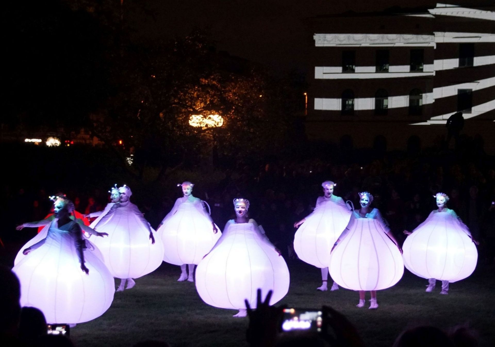 Un grupo de personas vestidas con vestidos blancos están bailando frente a una multitud.
