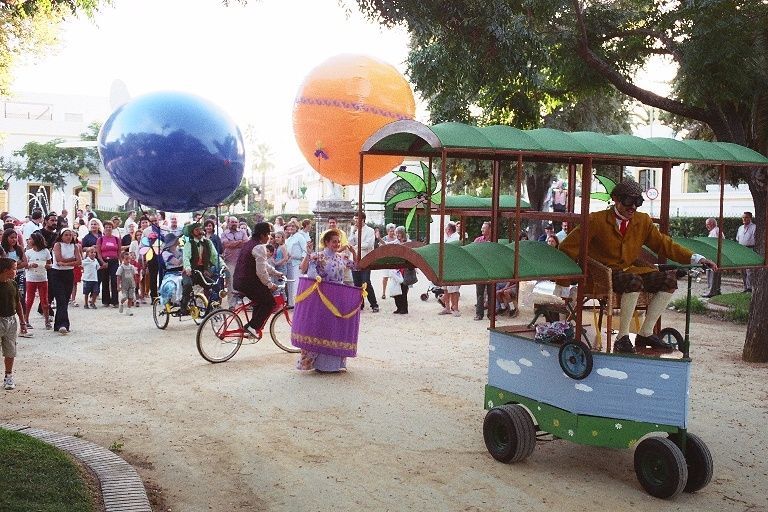 Un grupo de personas viajan en un carro con globos al fondo.