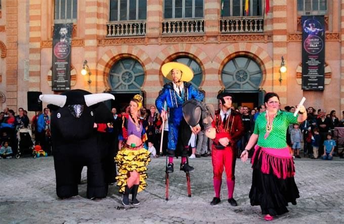 Un grupo de personas disfrazadas bailan frente a un edificio.