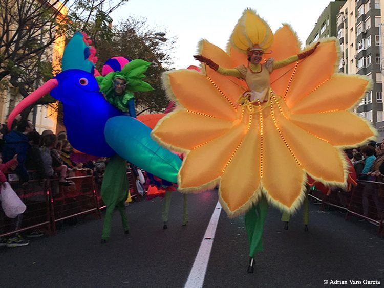Un desfile con personas vestidas de flores y pájaros
