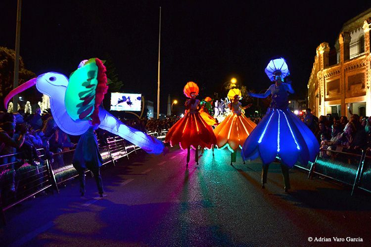 Un grupo de personas camina por una calle vistiendo disfraces que brillan en la oscuridad.