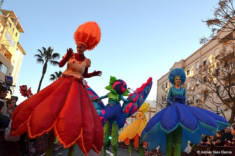 Un grupo de personas vestidas con trajes coloridos caminan por una calle.