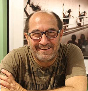 Un hombre con gafas y barba sonríe con los brazos cruzados.