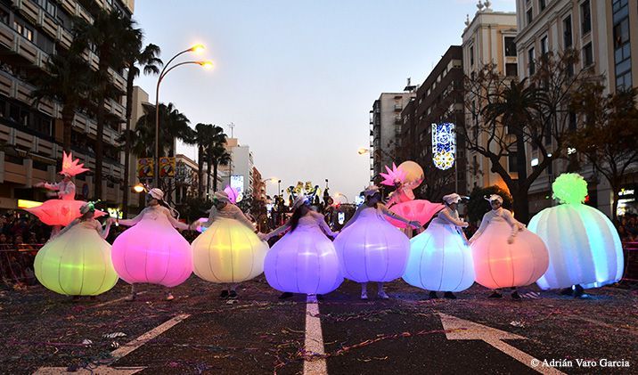 Un grupo de personas con vestidos coloridos caminan por una calle.