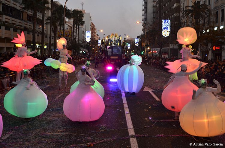Un grupo de personas camina por una calle con vestidos brillantes.
