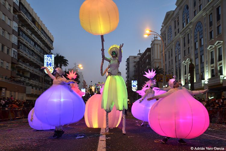 Un grupo de personas de pie sobre zancos sosteniendo globos en un desfile.