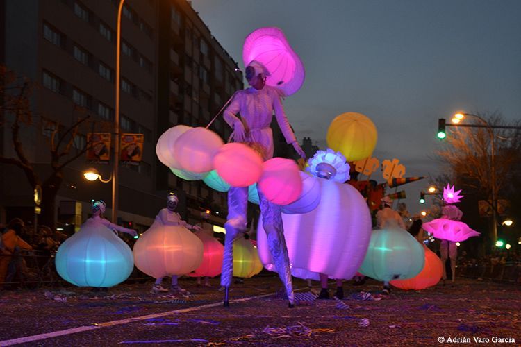 Un grupo de personas de pie sobre zancos con globos en sus manos.