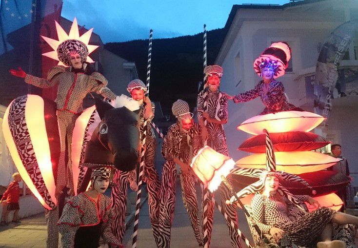 Un grupo de personas con trajes coloridos caminan sobre zancos.
