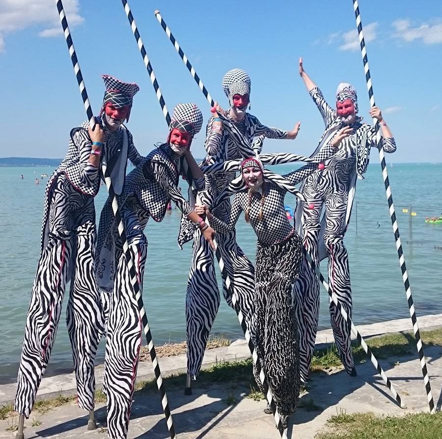 Un grupo de personas paradas sobre zancos frente a un cuerpo de agua