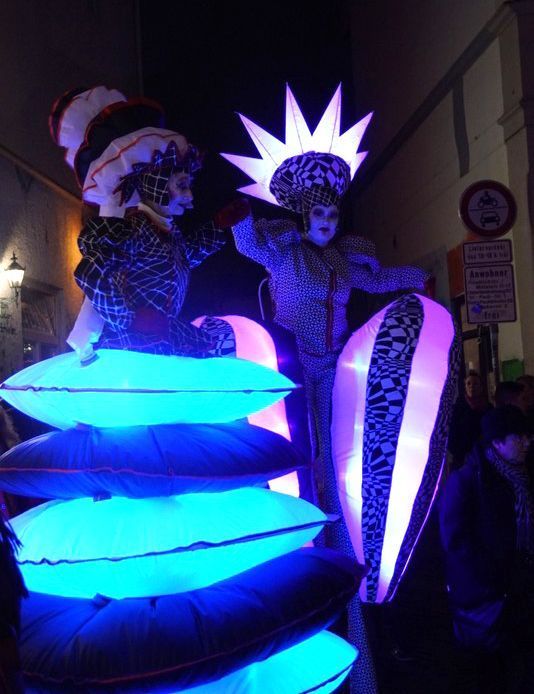 Un par de personas paradas sobre zancos con luces azules.