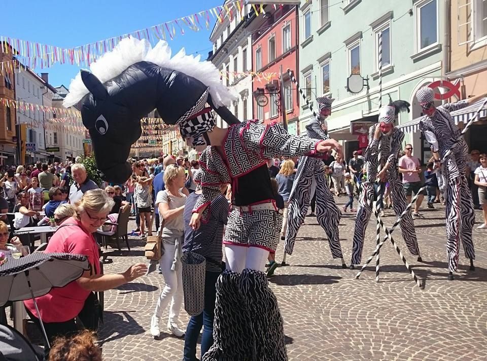 Un grupo de personas de pie sobre zancos delante de un gran caballo inflable.