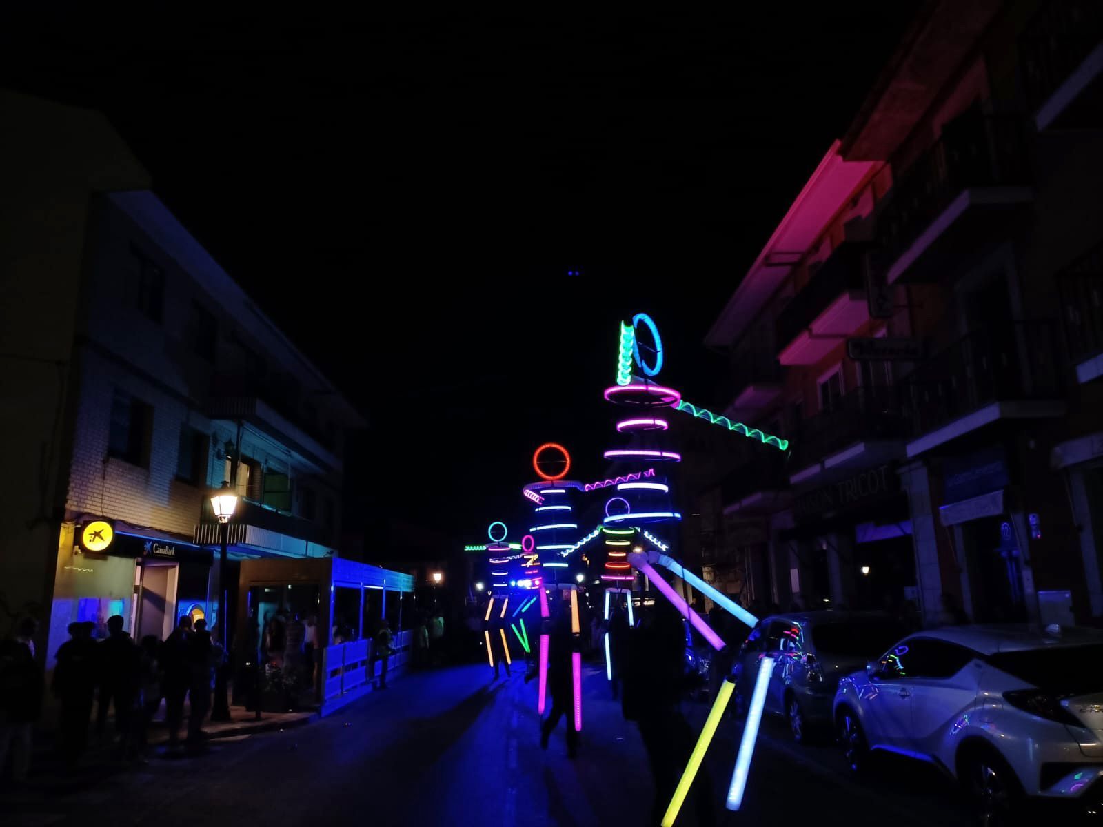 Un grupo de personas camina por una calle iluminada con luces de neón.