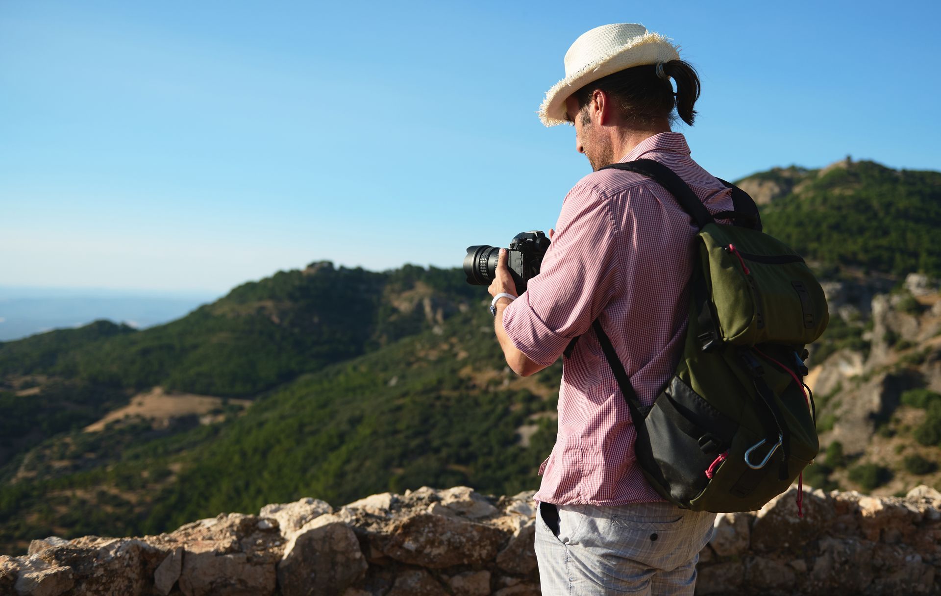 Un homme avec un sac à dos prend une photo d'une montagne.