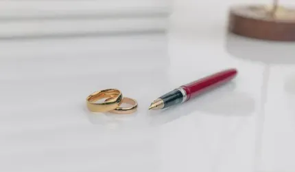 Un par de anillos de boda y un bolígrafo están sobre una mesa.