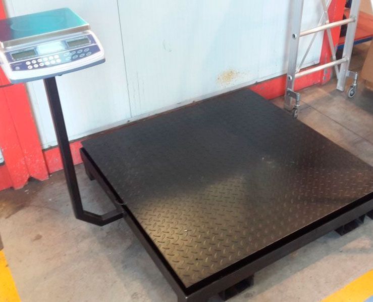 Una gran balanza está sentada sobre un piso de concreto al lado de una escalera.